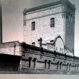 La fabbrica, costituita da edifici in pietra e alte ciminiere...